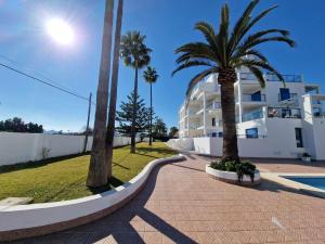 a street with palm trees and a white building at V19 Ático con impresionantes vistas al mar B16 in Denia