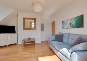 un soggiorno con divano blu e TV di Seablue Loft a Woolacombe