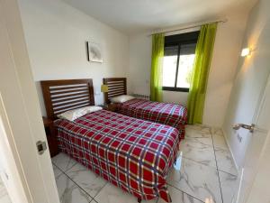 2 Betten in einem kleinen Zimmer mit grünen Vorhängen in der Unterkunft Corvera Hills, Corvera Golf and country club in Corvera