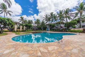 a swimming pool at a resort with palm trees at Sunset Villa - Walk To Koolina Beaches - Sleeps 8 in Kapolei