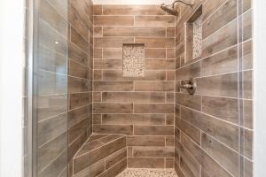 a bathroom with a shower with wooden tiles at Sunset Villa - Walk To Koolina Beaches - Sleeps 8 in Kapolei