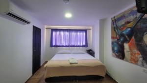 a bedroom with a bed and a window with a painting at Hotel Tayromar in Santa Marta