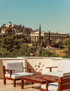 eine Terrasse mit 2 Stühlen, einem Tisch und einem Gebäude in der Unterkunft Suitas in Athen