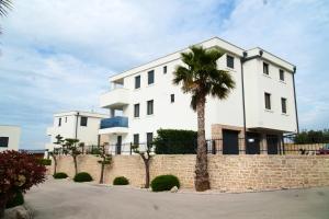a white building with a palm tree in front of it at Luxury apartment Mon Soleil in Murter