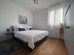 een witte slaapkamer met een groot bed met witte lakens bij Luxury apartment Mon Soleil in Murter