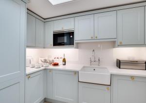 a white kitchen with white cabinets and a sink at St Agnes Sleeps 6 in Ilfracombe