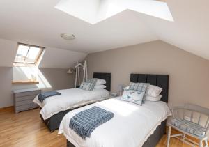 a attic bedroom with two beds and a window at The Stables in Braunton