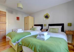a bedroom with two beds with green and white sheets at The Stables Lynton in Lynmouth