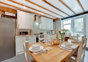 a kitchen with a wooden table with white cabinets at Temperance Cottage in Braunton