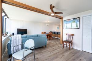 sala de estar con sofá azul y comedor en Sunset Shores - Waialua Oceanfront Retreat, en Waialua