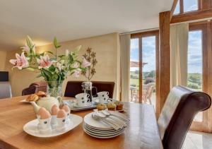 Threshing Barn في Bampton: طاولة طعام مع بيض و إناء من الزهور