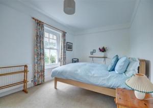 1 dormitorio con cama con sábanas azules y ventana en Treknow, en Combe Martin
