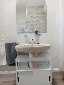 La salle de bains blanche est pourvue d'un lavabo et d'un miroir. dans l'établissement Milladoiro, à Teo