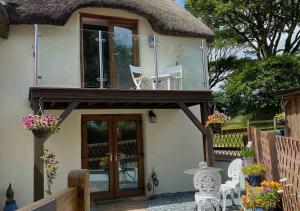 a small cottage with a thatched roof and a glass door at Thyme at South Worden 