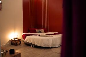 a small bedroom with a bed with red walls at Ignite Love Room in Nantes