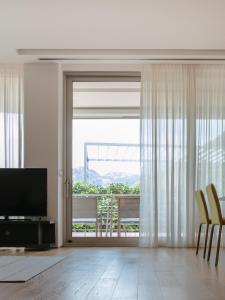 ein Wohnzimmer mit einem TV und einer Glasschiebetür in der Unterkunft Two-bedroom luxury apartment 2 mins to the sea in Budva