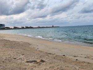 a sandy beach with the ocean on a cloudy day at Triple H Minionstay Kuala Terengganu in Kuala Terengganu