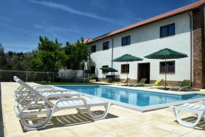 Una piscina con sillas y sombrillas al lado de un edificio. en Spacious Villa in Celorico de Basto with Private Pool, en Celorico de Basto