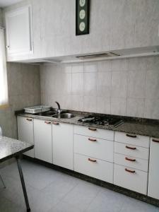 a kitchen with white cabinets and a sink and a stove at 4 bedrooms appartement at Bueu in Bueu