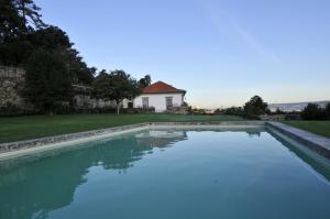 uma piscina de água com uma casa ao fundo em 6 bedrooms villa with private pool furnished garden and wifi at Santo Tirso em Santo Tirso