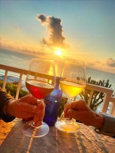 dos personas sosteniendo copas de vino en una mesa con la puesta de sol en Mediterranean Boutique Hotel, en Tropea
