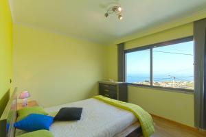 ポンタ・ド・ソルにある2 bedrooms house with sea view furnished terrace and wifi at Ponta do Sol 5 km away from the beachのベッドルーム1室(ベッド1台、大きな窓付)