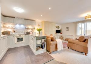 a large kitchen with two chairs and a living room at Wisteria Cottage in Parkham