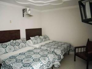 a bedroom with two beds and a chair at Hotel Central Johanna in Tuluá