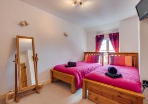 1 dormitorio con 2 camas y espejo en Willow Cottage, en Braunton