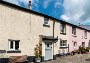 una casa con una puerta azul y un banco en Willow Cottage, en Braunton