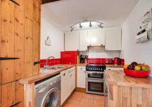a kitchen with white cabinets and a washing machine at Willow Cottage in Braunton
