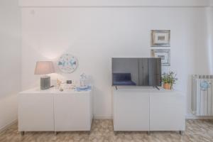 a living room with a tv on top of white cabinets at RAPALLO APARTMENT Comodo e in Ottima Posizione in Rapallo