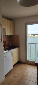 een keuken met uitzicht op het water en een raam bij Ancre et Mouettes in Saint-Cyprien