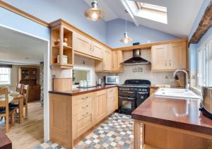 uma cozinha com armários de madeira e um forno com placa de fogão em Wisteria Cottage em Great Torrington