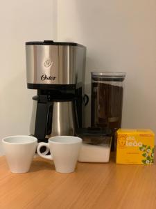 a coffee maker with two cups and a box on a table at Apart Hotel Centro de Brasília (Garvey Park Hotel) in Brasilia