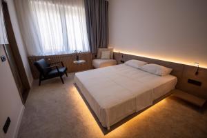 Habitación de hotel con cama y silla en Bloom Suites en Pristina