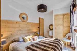 a bedroom with a bed with a wooden wall at La Suite Édelweiss - Welkeys in Combloux