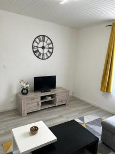 uma sala de estar com um relógio na parede em Richelieu 2 chez Adrien em Saint-Quentin