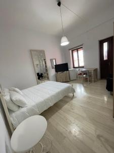 a large white bedroom with a bed and a table at Aphaias Apartments in Aegina Town