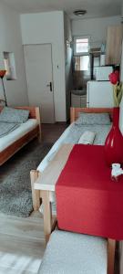 a room with two beds and a red vase on a table at Napfény Apartmanház Balatonberény in Balatonberény