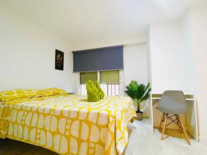 ein Schlafzimmer mit einem gelben und weißen Bett und einem Stuhl in der Unterkunft Guest House Leo in Alicante