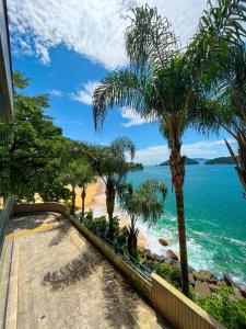 een uitzicht op een strand met palmbomen en de oceaan bij Apartamento LUXO no Porto Real Resort ao lado da praia in Mangaratiba