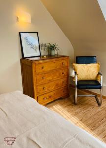 ein Schlafzimmer mit einer Holzkommode und einem Stuhl in der Unterkunft BeauVenue in Veurne