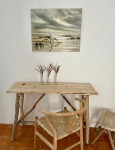 einem Holztisch mit zwei Vasen und einem Gemälde an der Wand in der Unterkunft Domaine de Bonelli in Conqueyrac