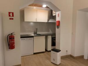 cocina con armarios blancos y extintor de incendios en Fazenda Apartments - Apartment 3, en Lajes das Flores