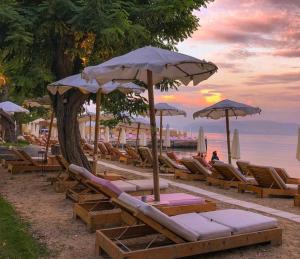a group of lounge chairs and umbrellas on a beach at Vasiliki Little House in Kanoni