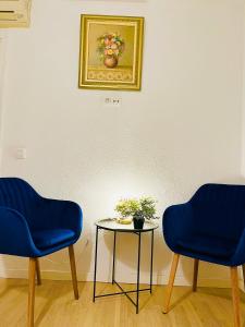 zwei blaue Stühle und ein Tisch mit einem Bild an der Wand in der Unterkunft Guest House Leo in Alicante