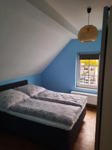 een slaapkamer met een bed met een blauwe muur en een raam bij Wohnung in Bad Lippspringe in Bad Lippspringe