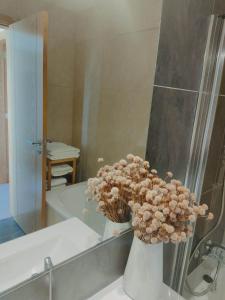 a white vase with flowers in a bathroom at Douro Valley Terrace Apartments in Armamar