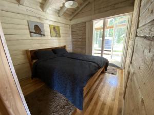 a bedroom with a bed in a wooden cabin at Pelėdų Namelis in Šlaveitai